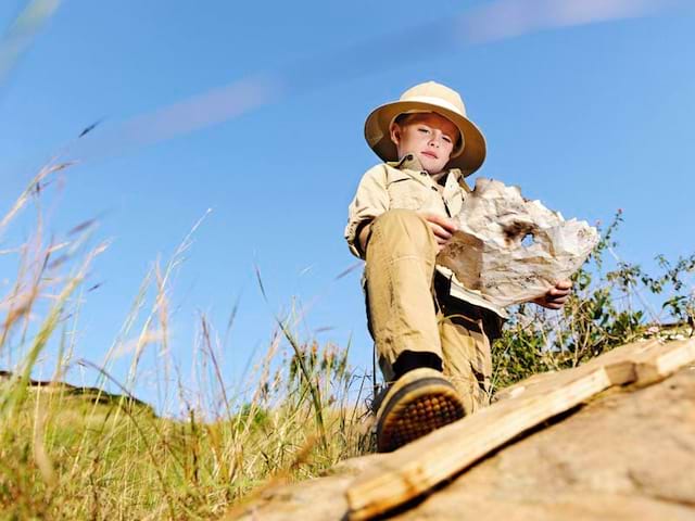 Enfant habillé en aventurier cherchant à se repérer grâce à une carte en colonie de vacances été