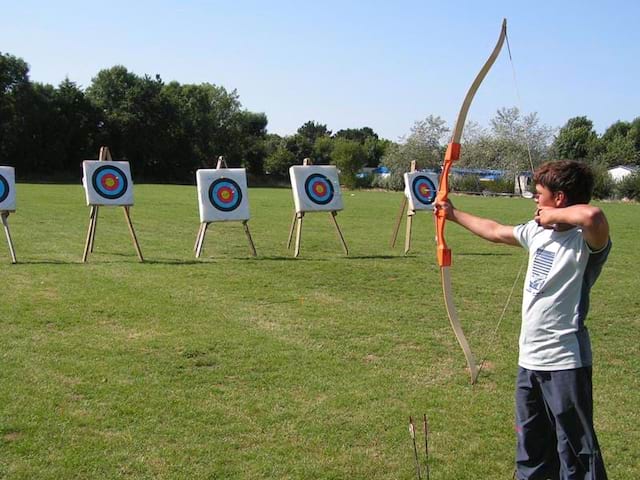 Enfant visant des cibles de tir à l'arc en colonie de vacances multi activités de sports été