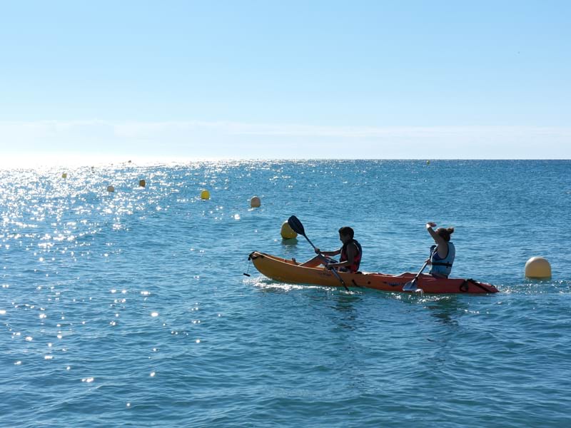 Enfants et adolescents faisant du canoe en colonie de vacances à l'océan