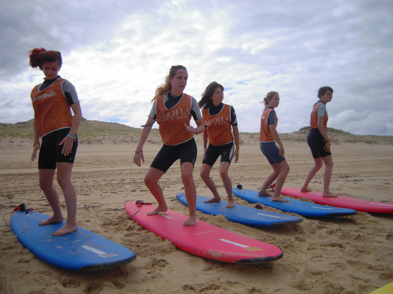 Adolescents apprenant la bonne posture sur un surf à la plage en colo