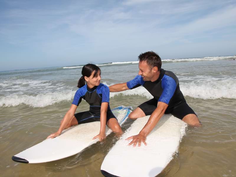 Moniteur de surf apprenant à une jeune fille à faire du surf en colonie de vacances