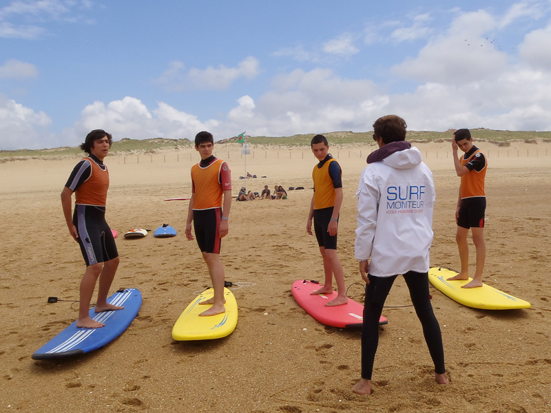 Moniteur de surf apprenant les bases à un groupe d'ados en colo de surf 