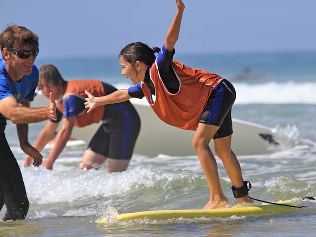 Jeune fille apprenant à trouver l'équilibre sur une planche de surf en colonie de vacances