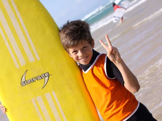 Enfant avec sa planche de surf en colonie de vacances d'été