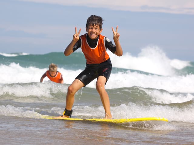 Enfants heureux de faire du surf en colonie de vacances d'été