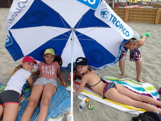 Enfants à la plage sous un parasol de colonie de vacances d'été