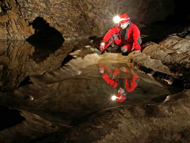 moniteur faisant de la spéléologie pour ados en colonie de vacances 