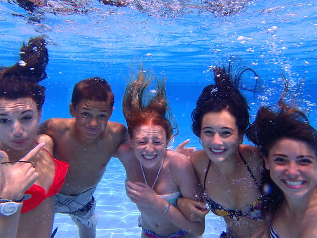 groupe d'ados sous l'eau dans la piscine de colo dans le sud