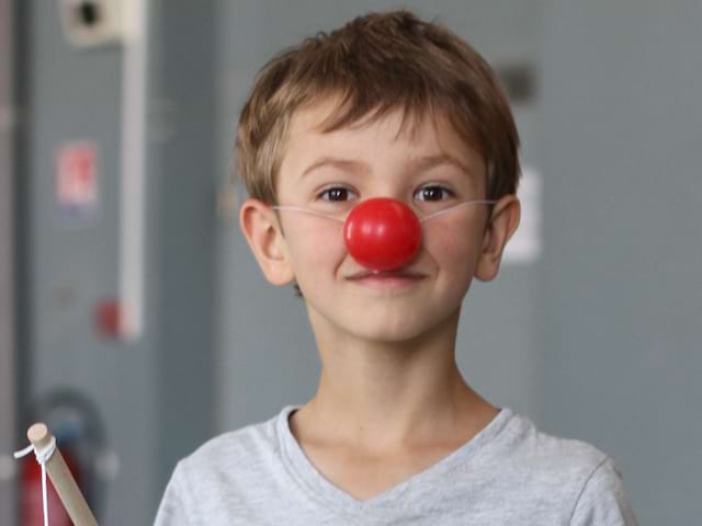 Jeune garçon portant un nez rouge de clown en colonie de vacances théatre