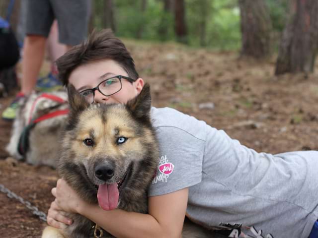 Enfant enlaçant un chien en colonie de vacances multiactivités été