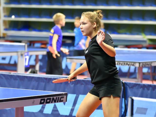 Jeune fille jouant au tennis de table à haut niveau durant un stage sportif 