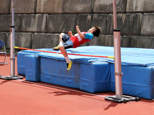 enfant s'entrainant au saut en hauteur durant un stage sportif d'athlétisme cet été