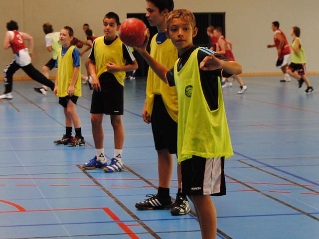 groupe d'enfants dans un gymnase cet été jouant au handball