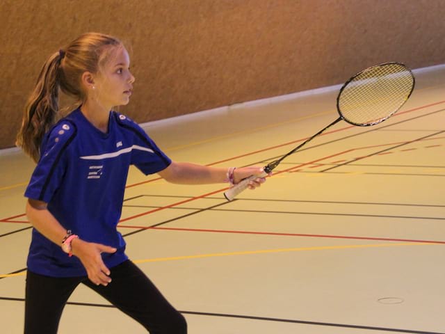 Jeune fille pratiquant le badminton à haut niveau en stage sportif de badminton