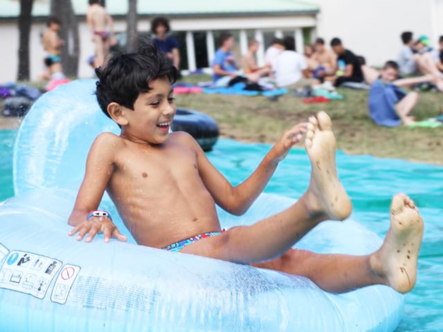 enfant faisant des glissades sur les jeux d'eaux du stage sportif