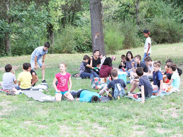 groupe d'enfants apprenant l'anglais en extérieur durant un stage sportif