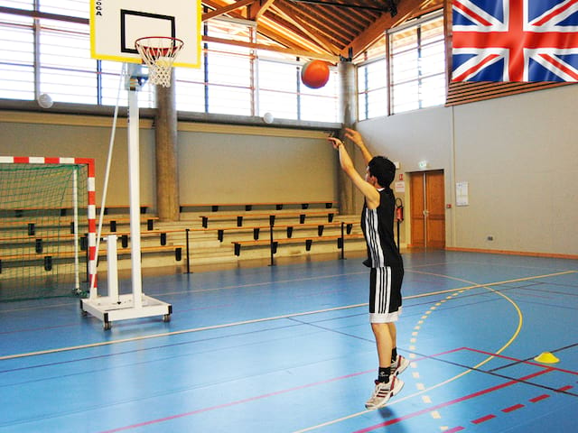 Adolescent jouant au basketball en stage sportif cet été