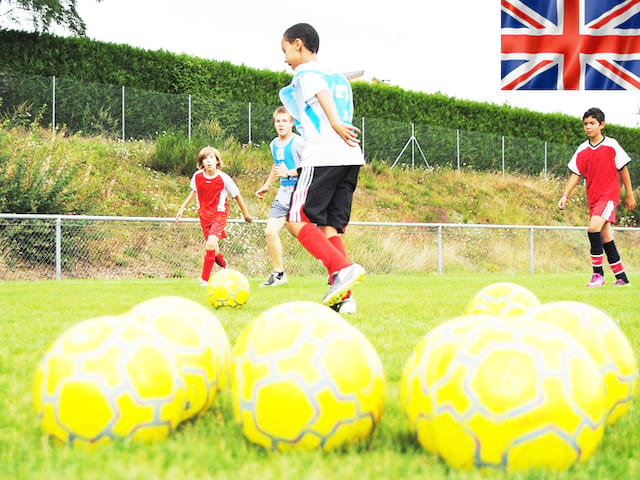 enfants et ados jouant au football durant un stage de football cet été