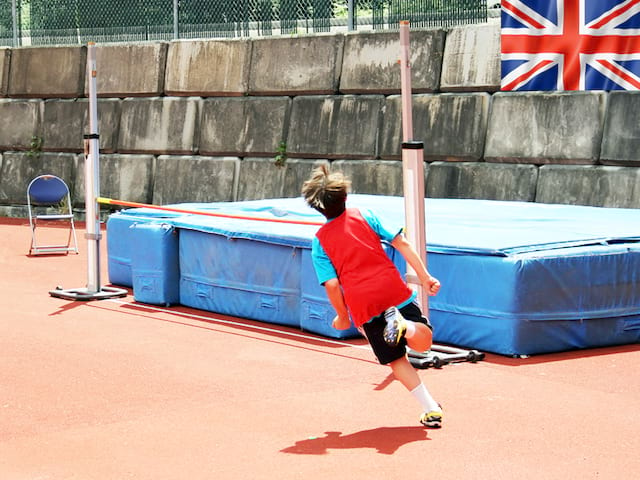 Enfant pratiquant le saut en hauteur en athlétisme cet été