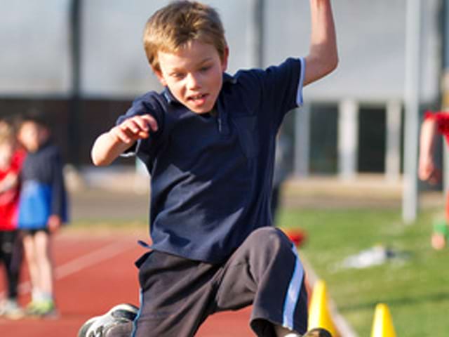 enfant en stage d'athlétisme faisant du saut de haie