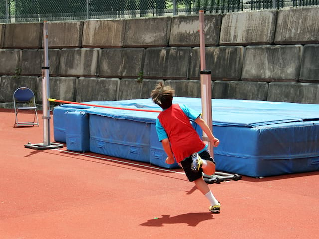 Enfant pratiquant le saut en hauteur en stage d'athlétisme cet été