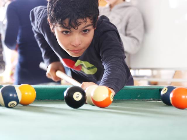 Enfant jouant au billard cet été durant un stage sportif 