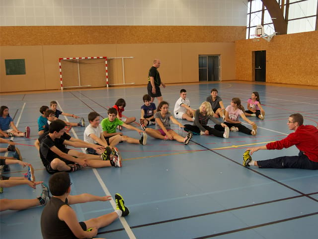 groupe d'enfants faisant des étirements avant un entrainement de badminton en stage sportif