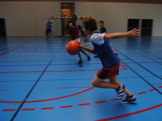 Enfant en train de jouer au basket durant un stage sportif de basketball