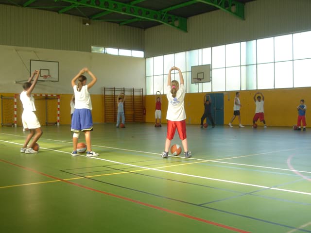 enfants jouant au basketball en intérieur en stage sportif d'été