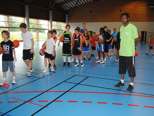 groupe d'enfants et ados en pleine partie de basketball cet été