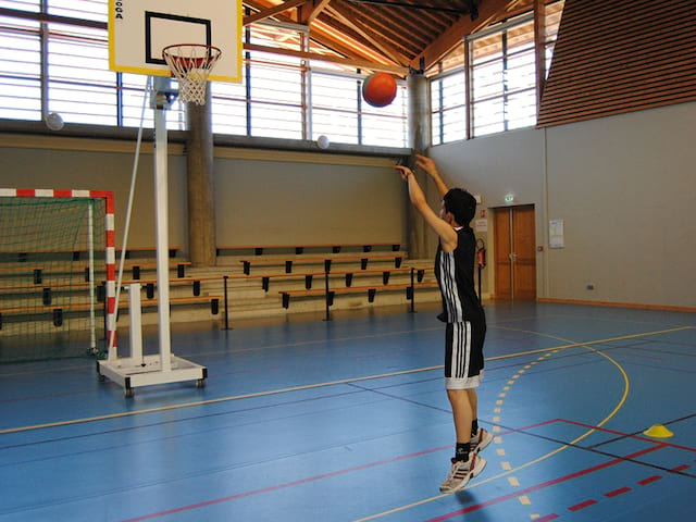 Adolescent jouant au basketball en été durant un stage sportif