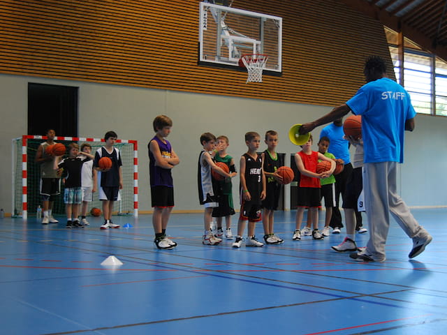 groupe d'enfants faisant du basketball en stage sportif