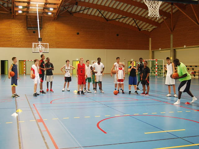 enfants et ados jouant au basketball en stage sportif cet été