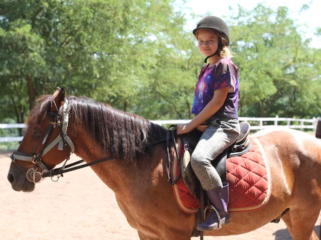 Ado sur un cheval en stage sportif d'équitation 