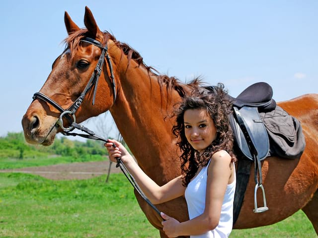 Jeune fille pratiquant l'equitation durant un stage sportif