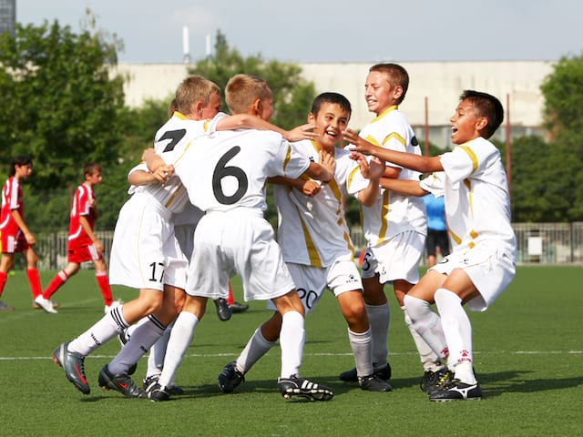 Groupe d'enfants heureux de faire du football en stage sportif de foot cet été