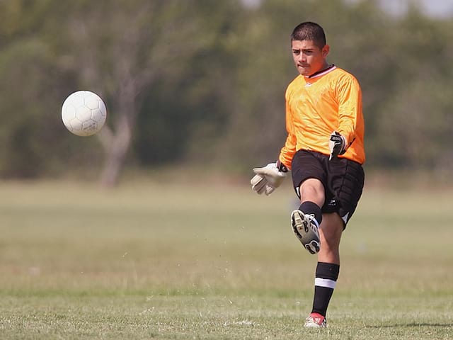 Adolescent s'entrainant au football cet été en stage sportif