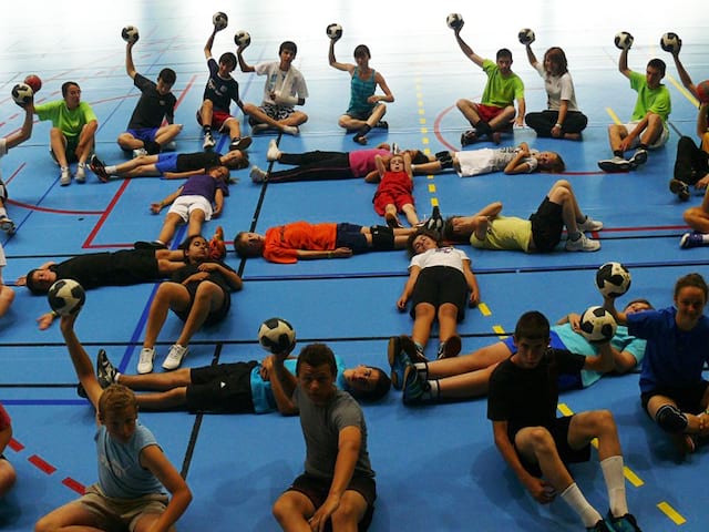 ados et enfants faisant des jeux de handball durant un stage sportif de handball cet été