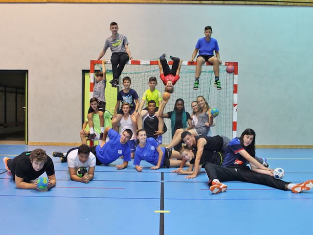 groupe d'enfants et ados jouant au handball en stage sportif cet été