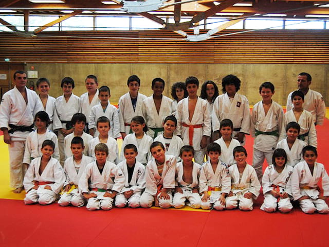 Groupe d'ados et enfants faisant du judo en stage sportif été