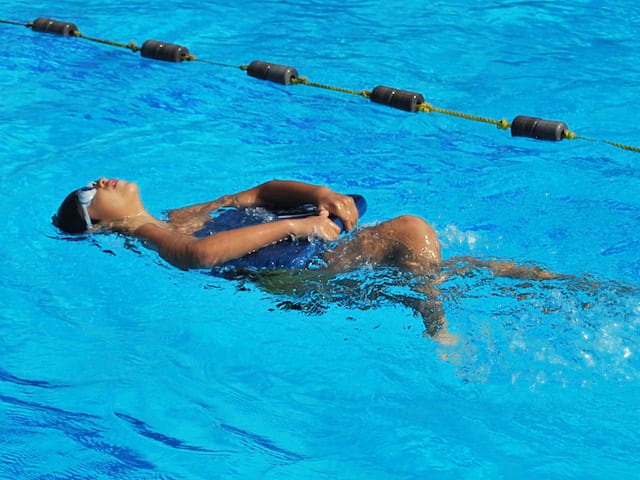 Enfant apprenant différentes techniques de nage en stage sportif d'été natation