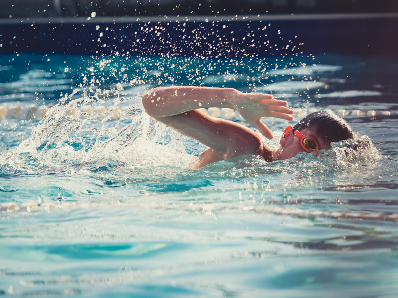 Jeune garçon apprenant à nager le crawl durant un stage sportif de natation