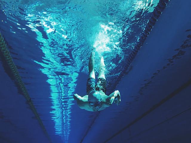 Ado apprenant la plongée en piscine durant un stage sportif de natation été