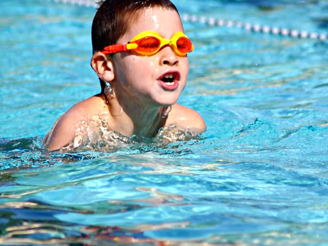 Enfant à la piscine avec des lunettes de plongée en stage sportif de natation cet été