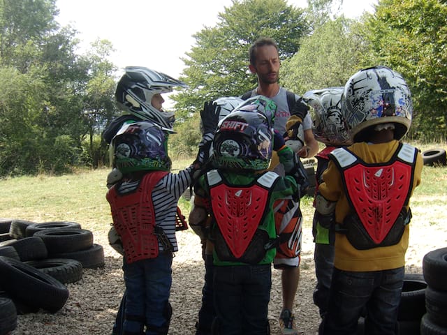 enfants et leur animateur de colonie de vacances apprenant à s'équiper pour faire de la moto en colo