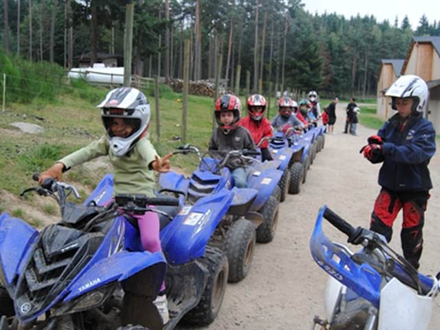 groupe d'enfants conduisant un quad les uns derrière les autres en stage sportif