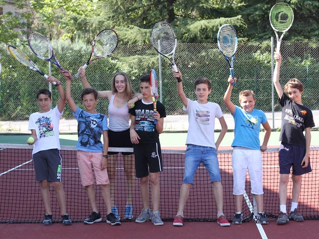 groupe d'enfants en colonie de vacances jouant au tennis 