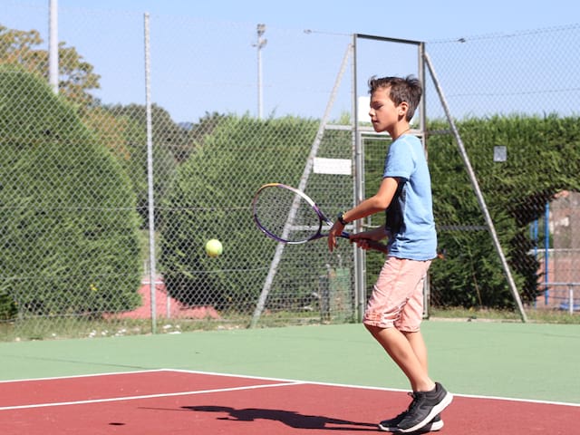 enfant jouant au tennis en stage sportif