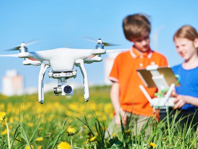 enfants apprenant ensemble à piloter le drone en colonie de vacances