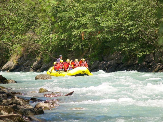 Groupe d'enfants et ados faisant du rafting en colonie de vacances à la montagne été